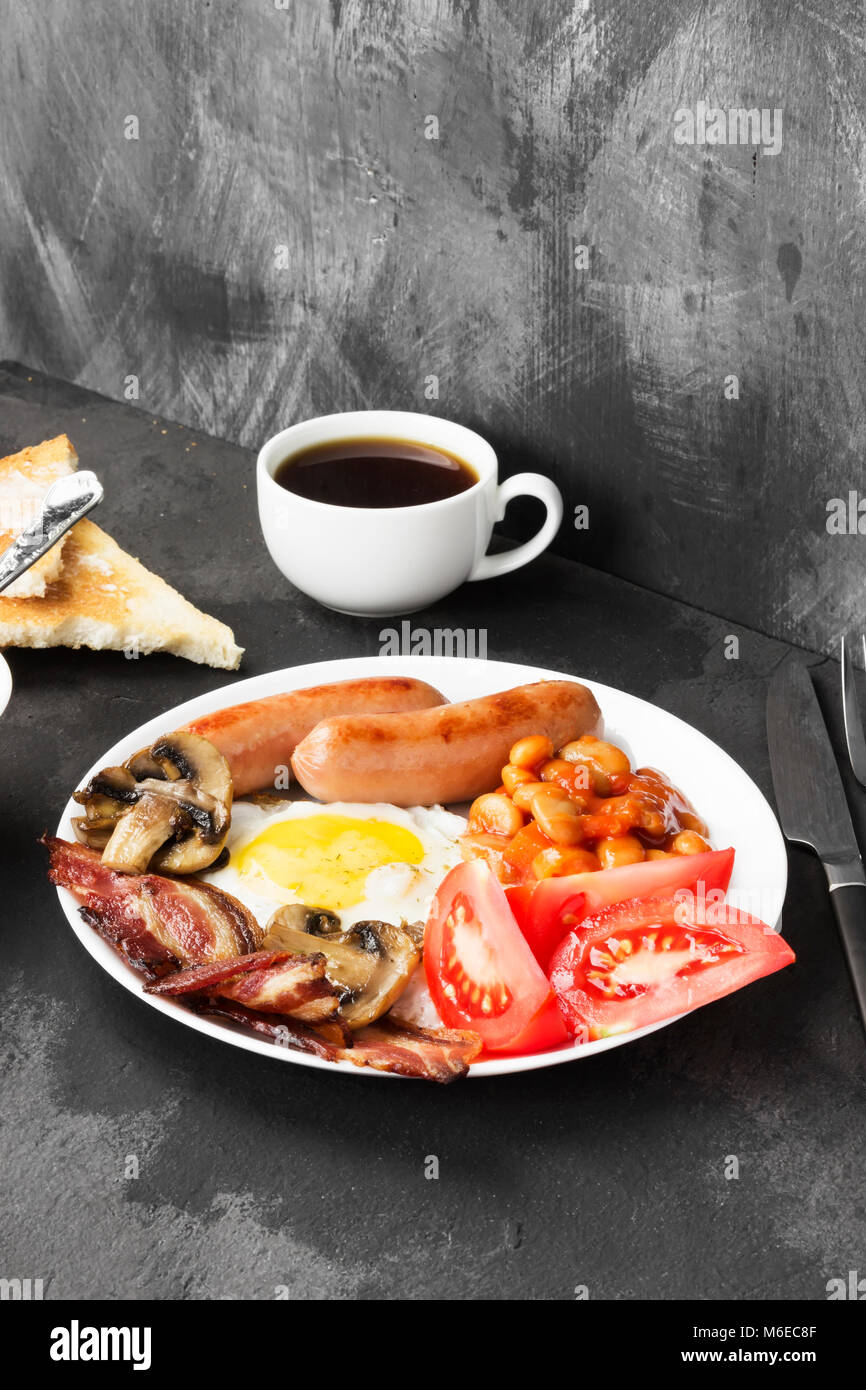 Traditional English breakfast bacon, sausages, fried eggs, tomatoes