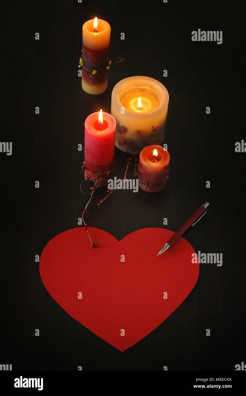 top view of love letter in shape of heart with candles and pen, vertical composition Stock Photo
