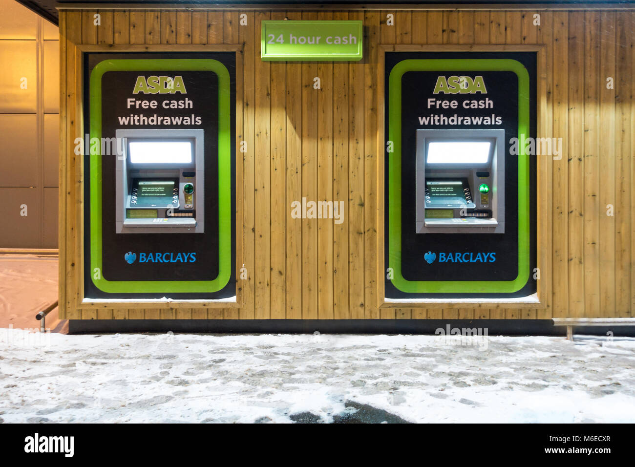 Cash machines in the side of an Asda supermarket, operated by Barclays bank, picture on a snowy night. Stock Photo