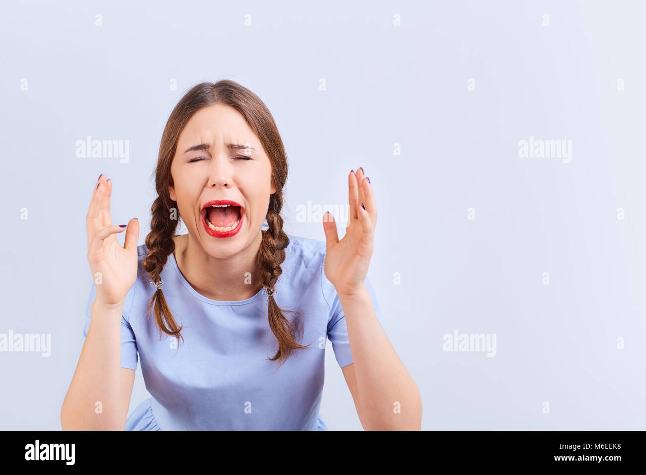 Young girl screams with emotion excited looking at gray background. Stock Photo