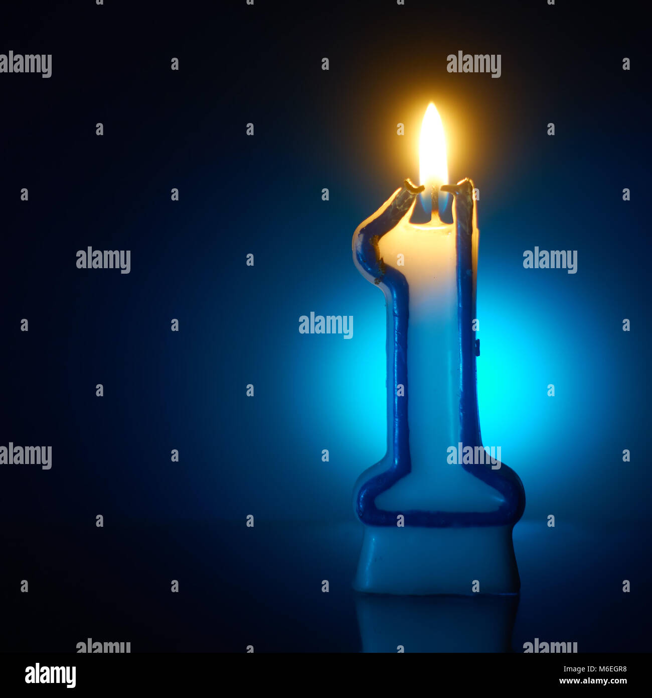 Number One - Burning birthday candle on blue background Stock Photo