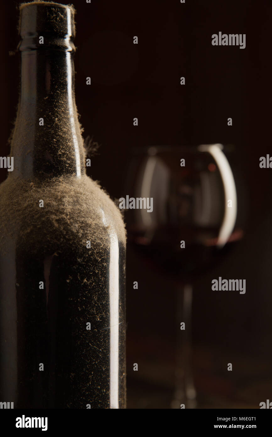 Dusty bottle of vintage wine and glass over dark background Stock Photo