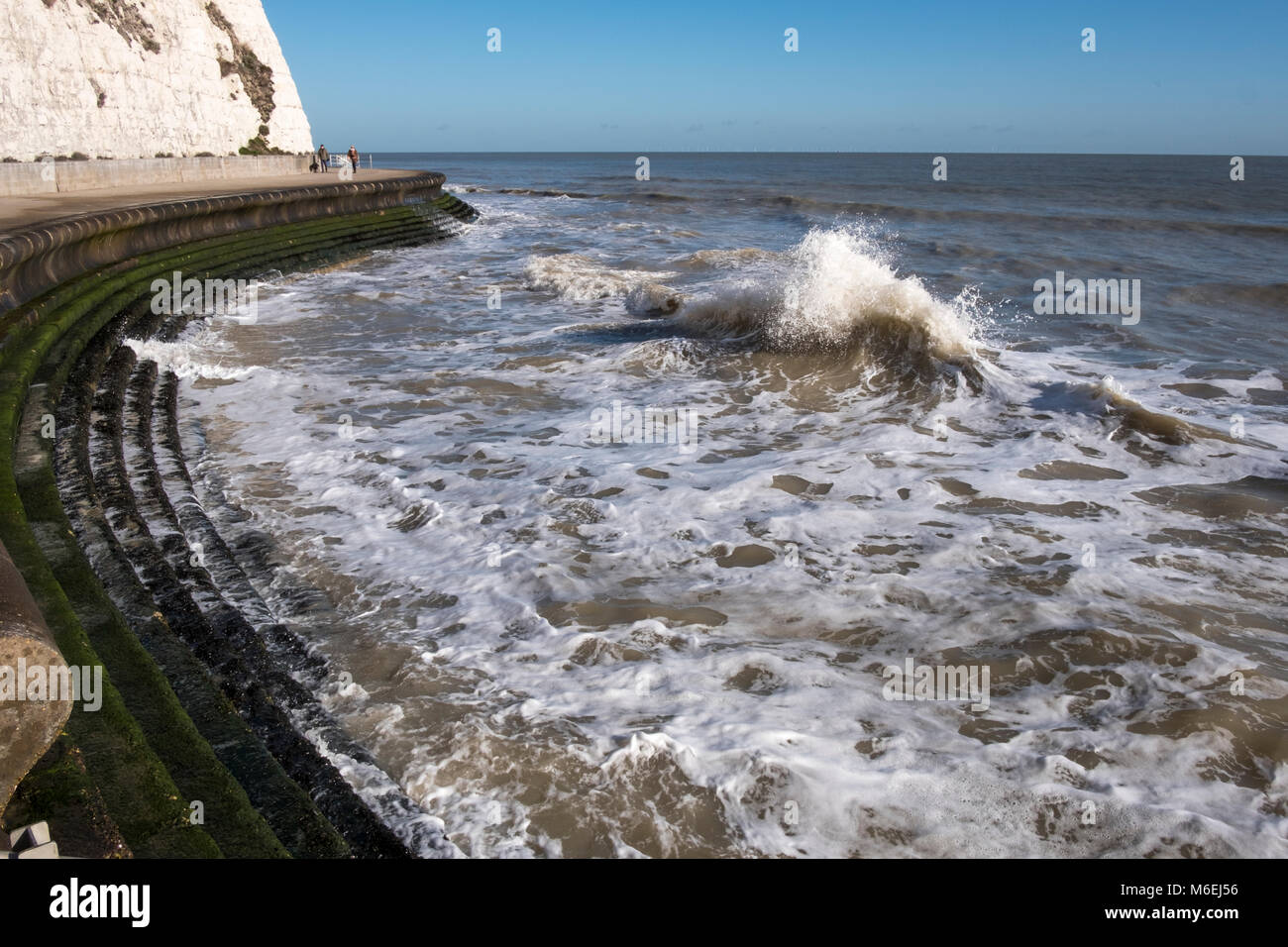 The high tide on the waterfront path near Broadstairs with the sea lapping on the promenade steps to the sandy beach. Stock Photo