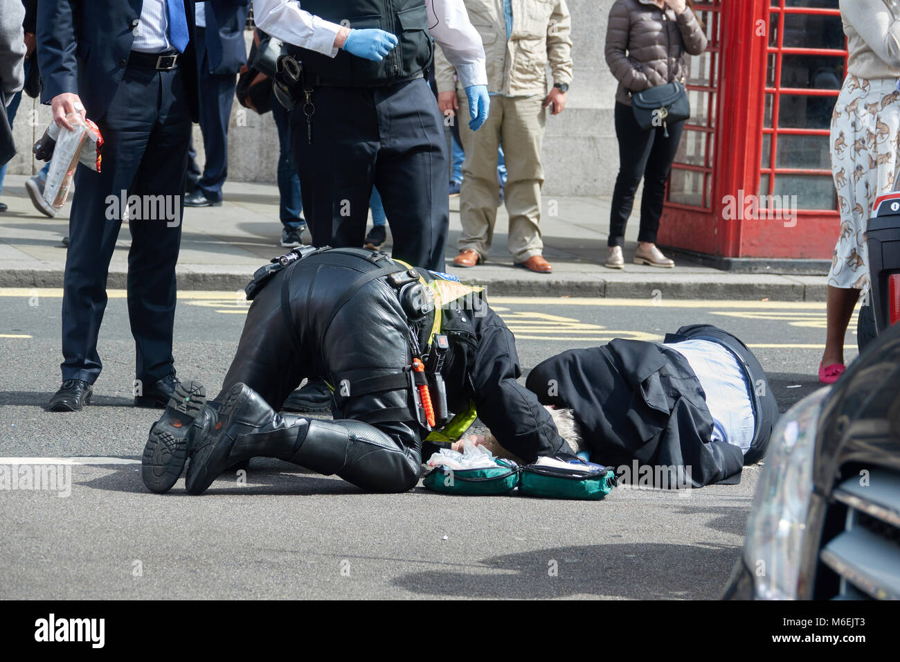 The policeman of London renders first aid to the pedestrian who suffered in the accident. Stock Photo