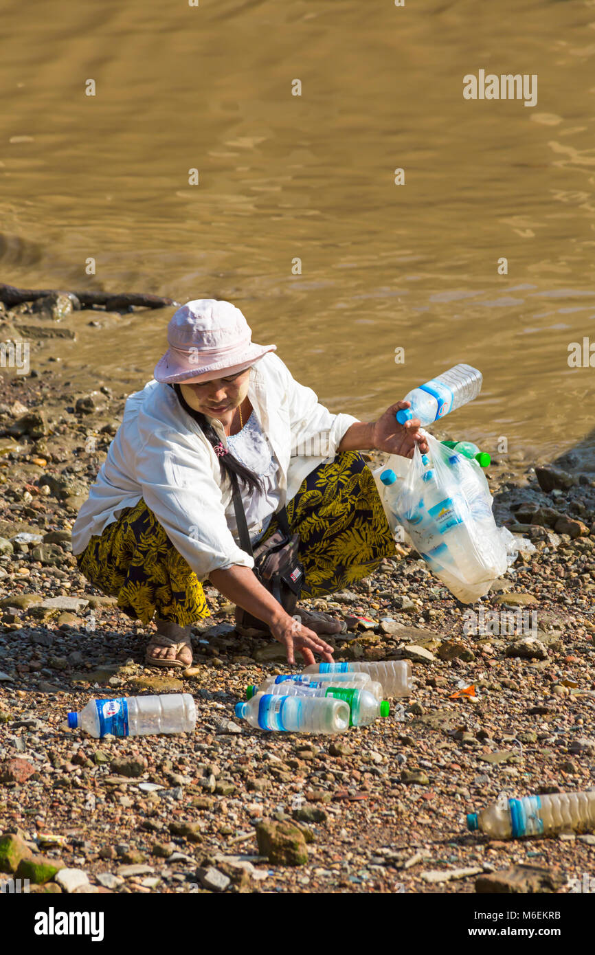 Woman picking up discarded plastic bottles for recycling at Nanthidar boat jetty, Yangon, Myanmar (Burma), Asia in February Stock Photo