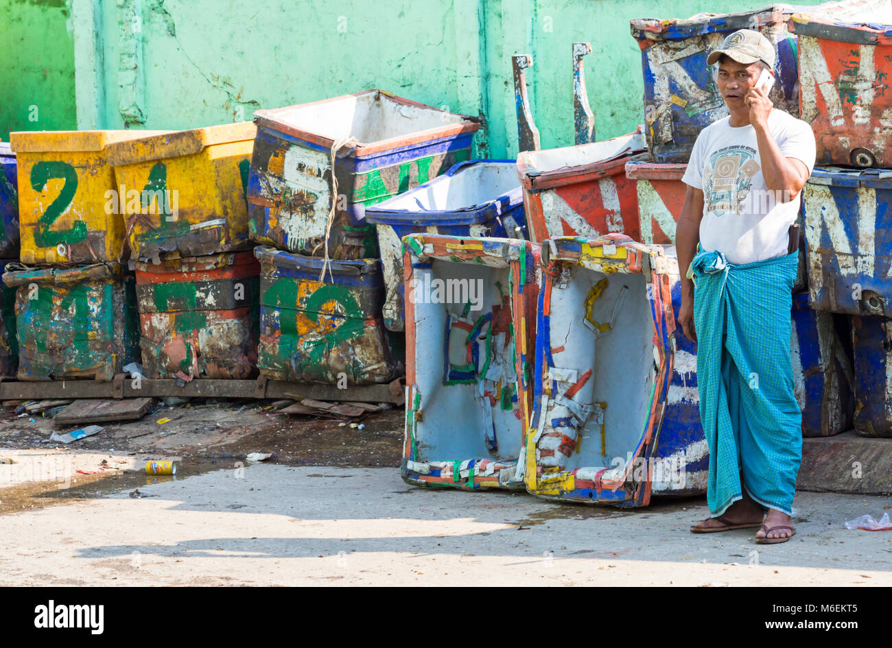 Man talking on mobile phone standing by empty crates at San Pya fish market, Yangon, Myanmar (Burma), Asia in February Stock Photo