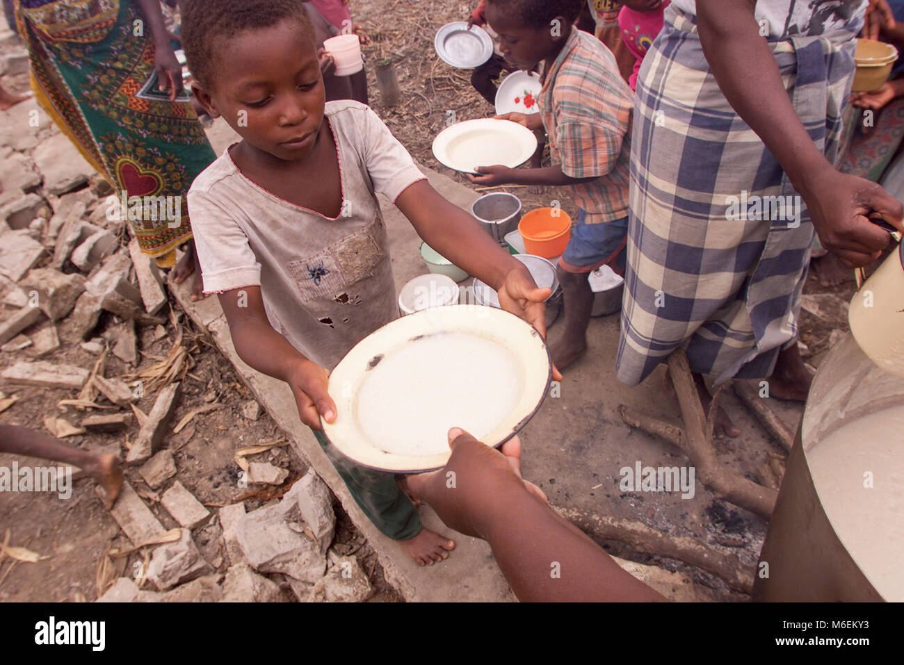 Floods in Mozambique  March 2000; A young boy takes a bowl maize porridge made with relief supplies at Pande camp for flood victims near Save town. Stock Photo