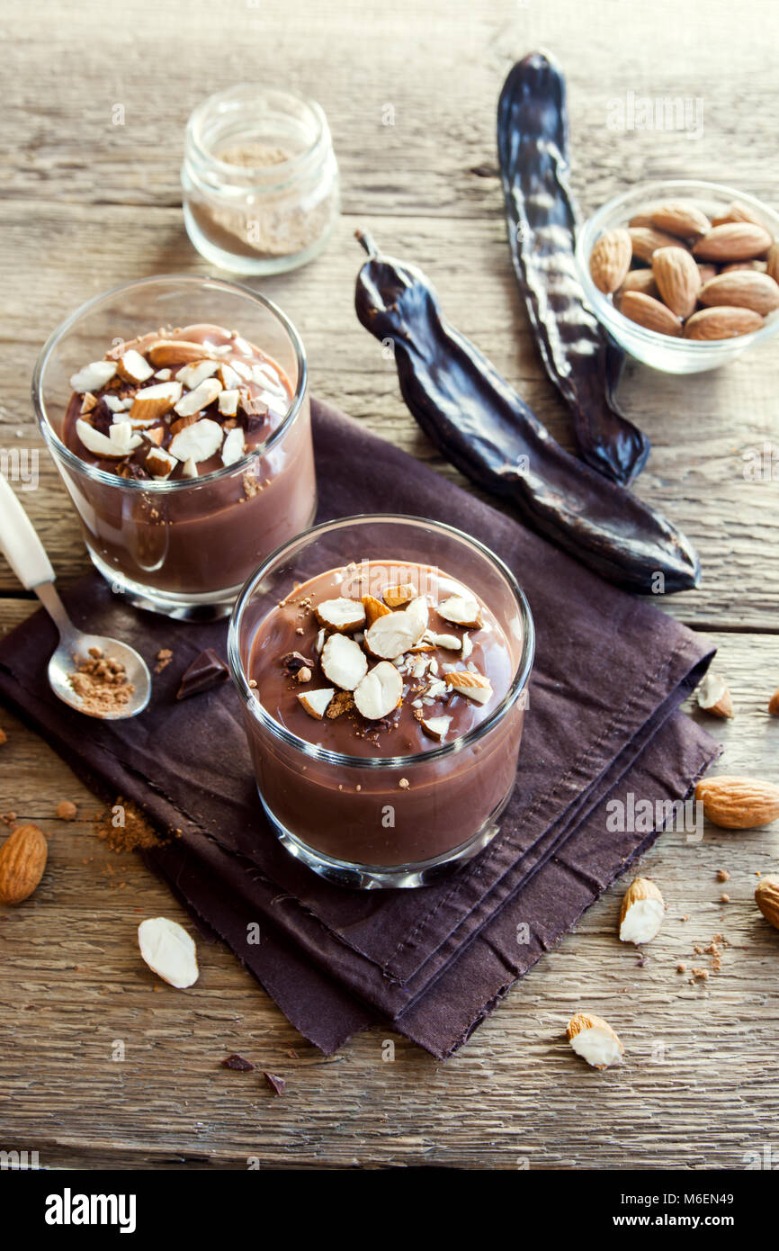 Chocolate (Carob) Mousse topped with Almond in glasses over wooden background close up - delicious homemade Raw Vegan Chocolate Pudding with Nuts and  Stock Photo