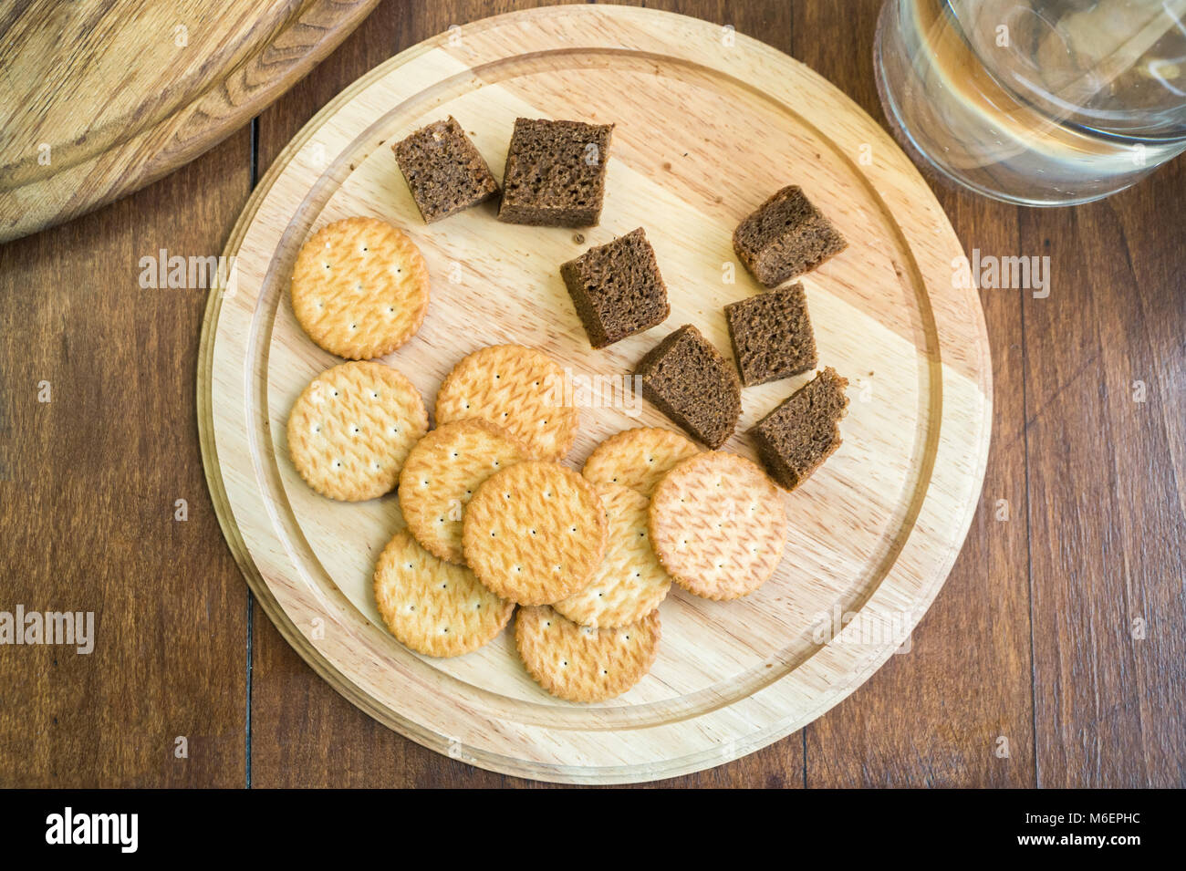 Top view of dry biscuits and corn bread as food sample. Biscuits and dark bread for degustation on a wood plate and water jar, flat lay Stock Photo