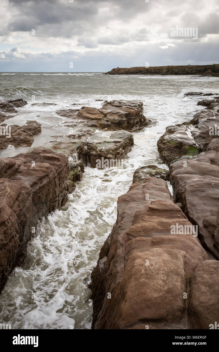 The sea on Northumbria coast UK in winter showing rough sea eroding rocks Stock Photo