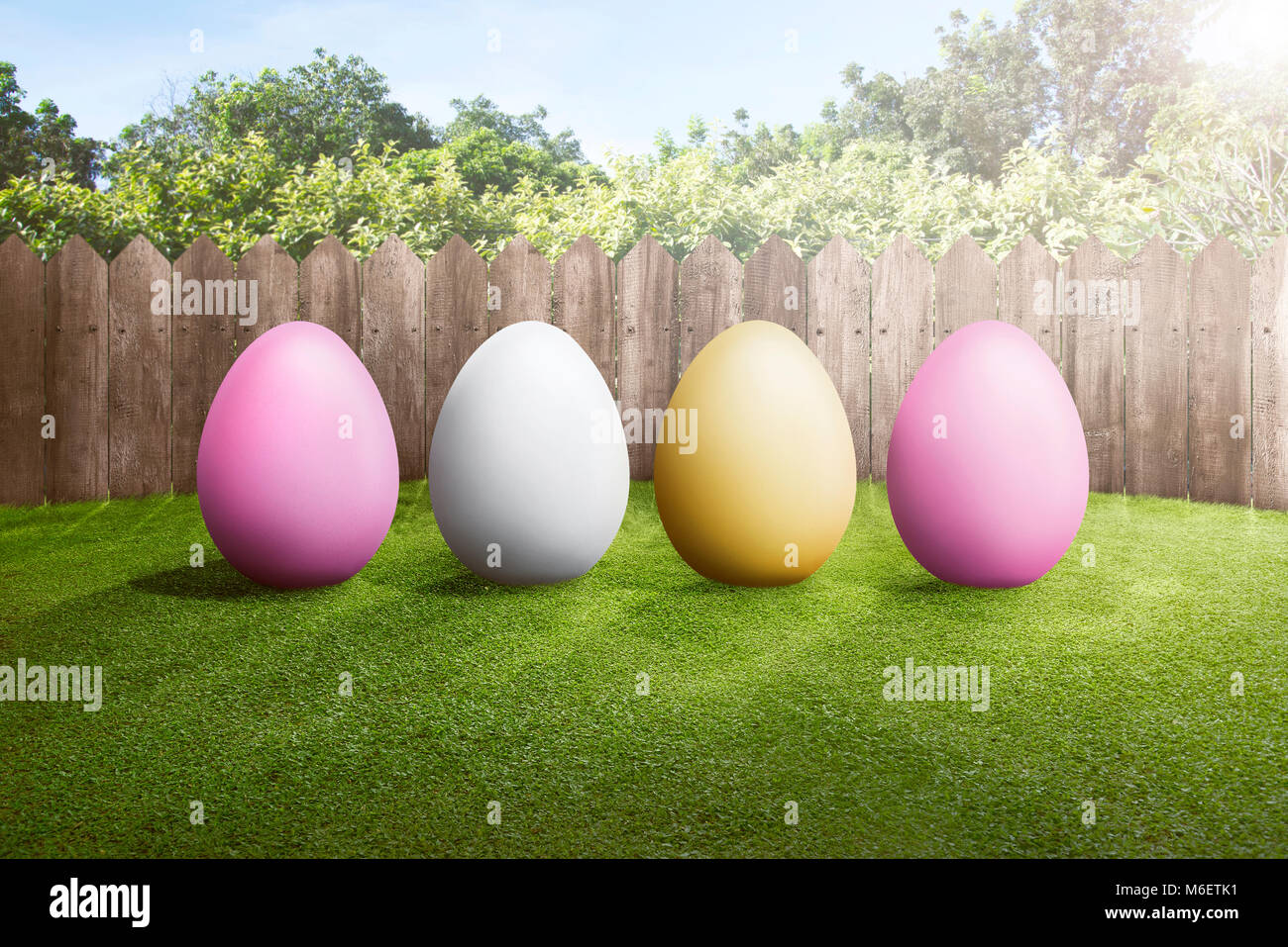 Row of colorful easter eggs on green grass with wooden fence background ...