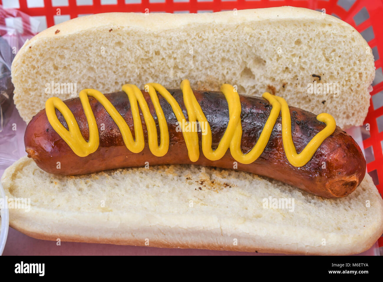 Classic hot dog with mustard on white bun representing American fast food and simple casual meal. Stock Photo