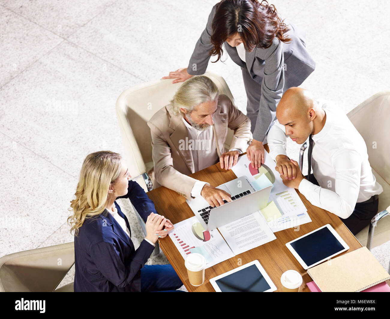 multinational and multiethnic corporate executives meeting in office discussing business performance, high angle view. Stock Photo