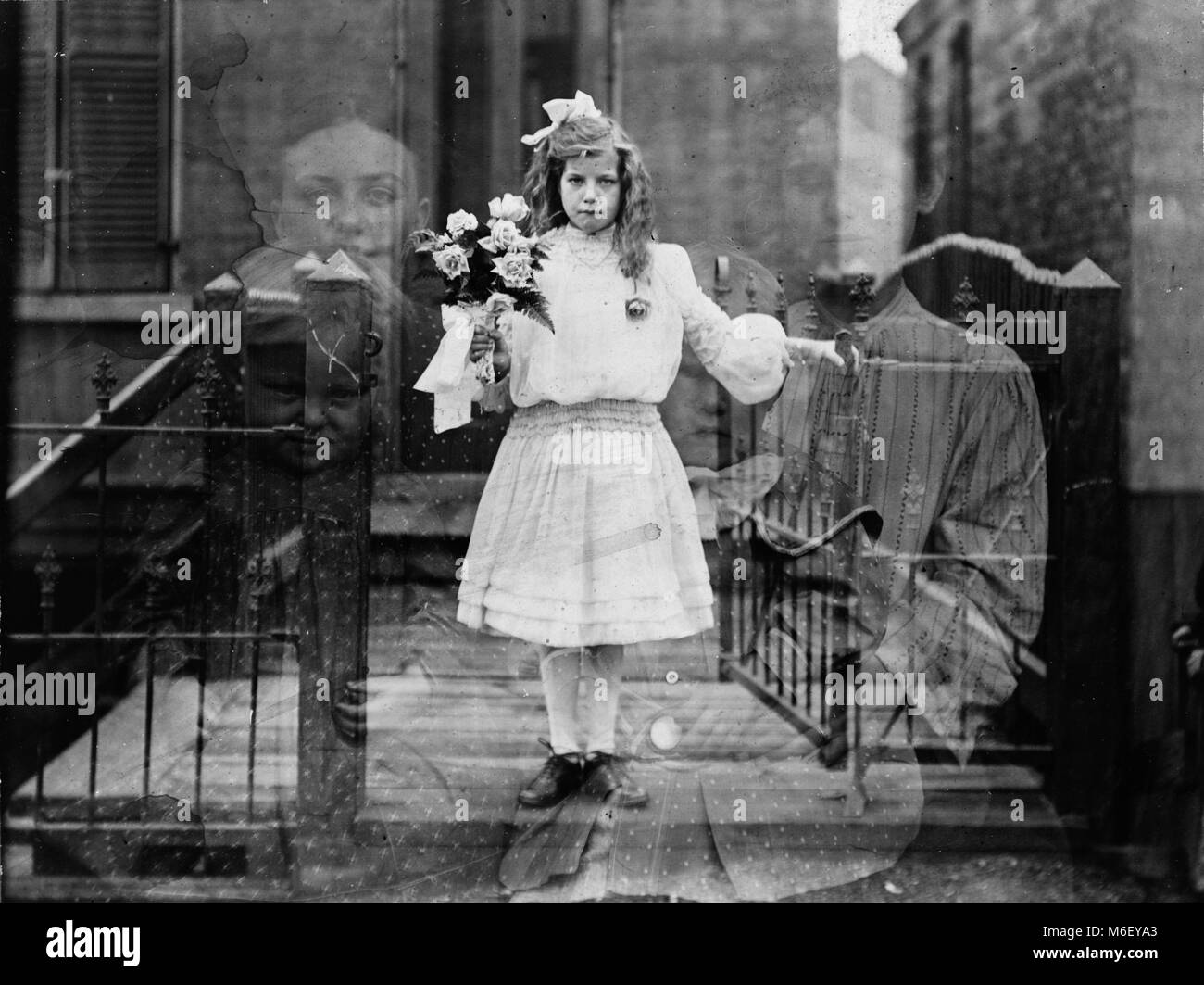 Double exposure spirit photograph showing a girl holding a flower bouquet surrounded by four ghostly figures, Chicago, IL, 1905. Stock Photo