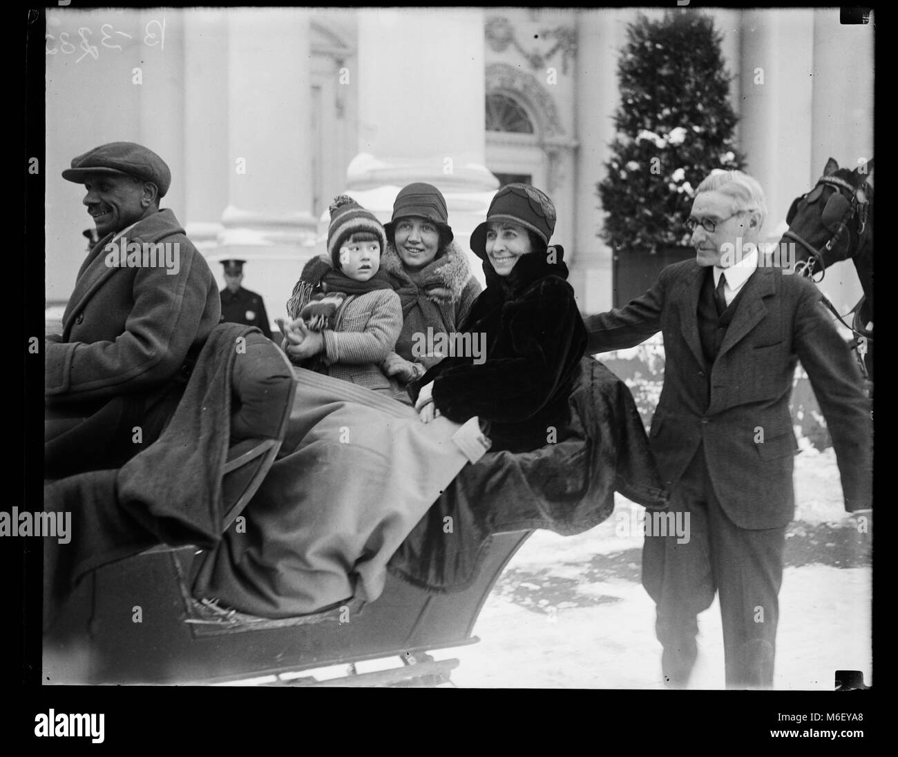 First Lady Grace Coolidge (center), seated by Chief White House Usher Ike Hoover (right), enjoys a sleigh ride on White House grounds with unidentified woman, child and driver, Washington, DC, 1929. Stock Photo