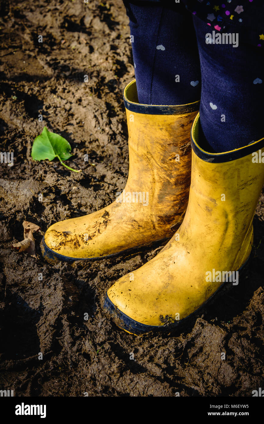 Dirty yellow children's wellies in the mud in the winter Stock Photo