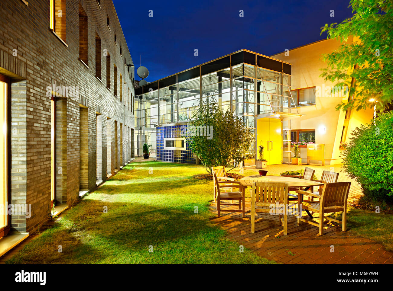 View of A modern office building with an outdoor sitting area with night blue ...