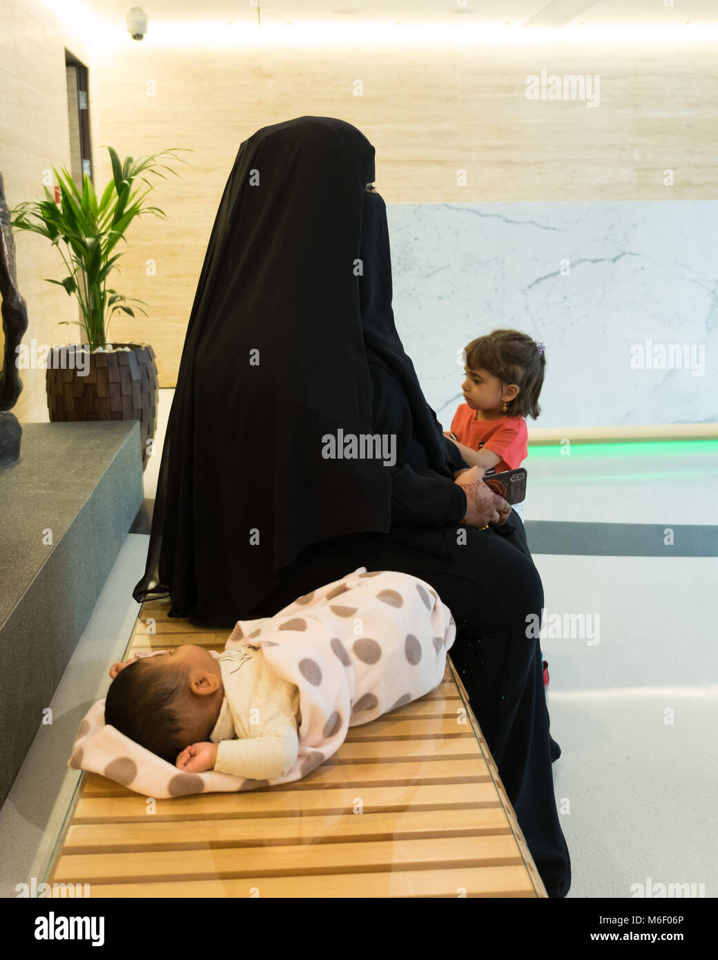 Arabic Woman With Young Daughter And Sleeping Baby On The Bench