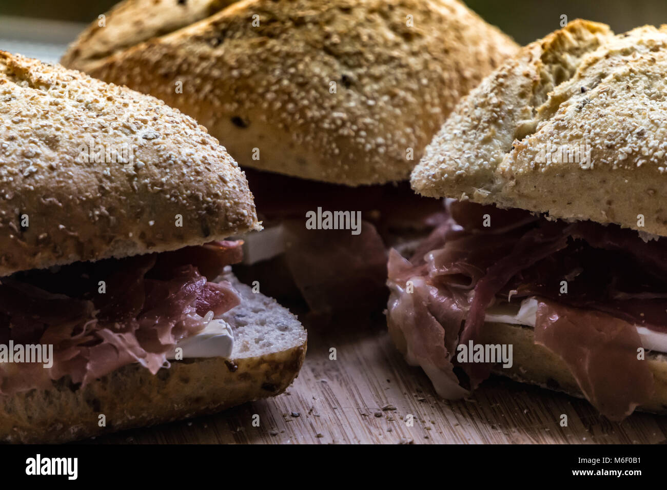 Close up shot of three sandwiches with whole grain bread, serrano ham