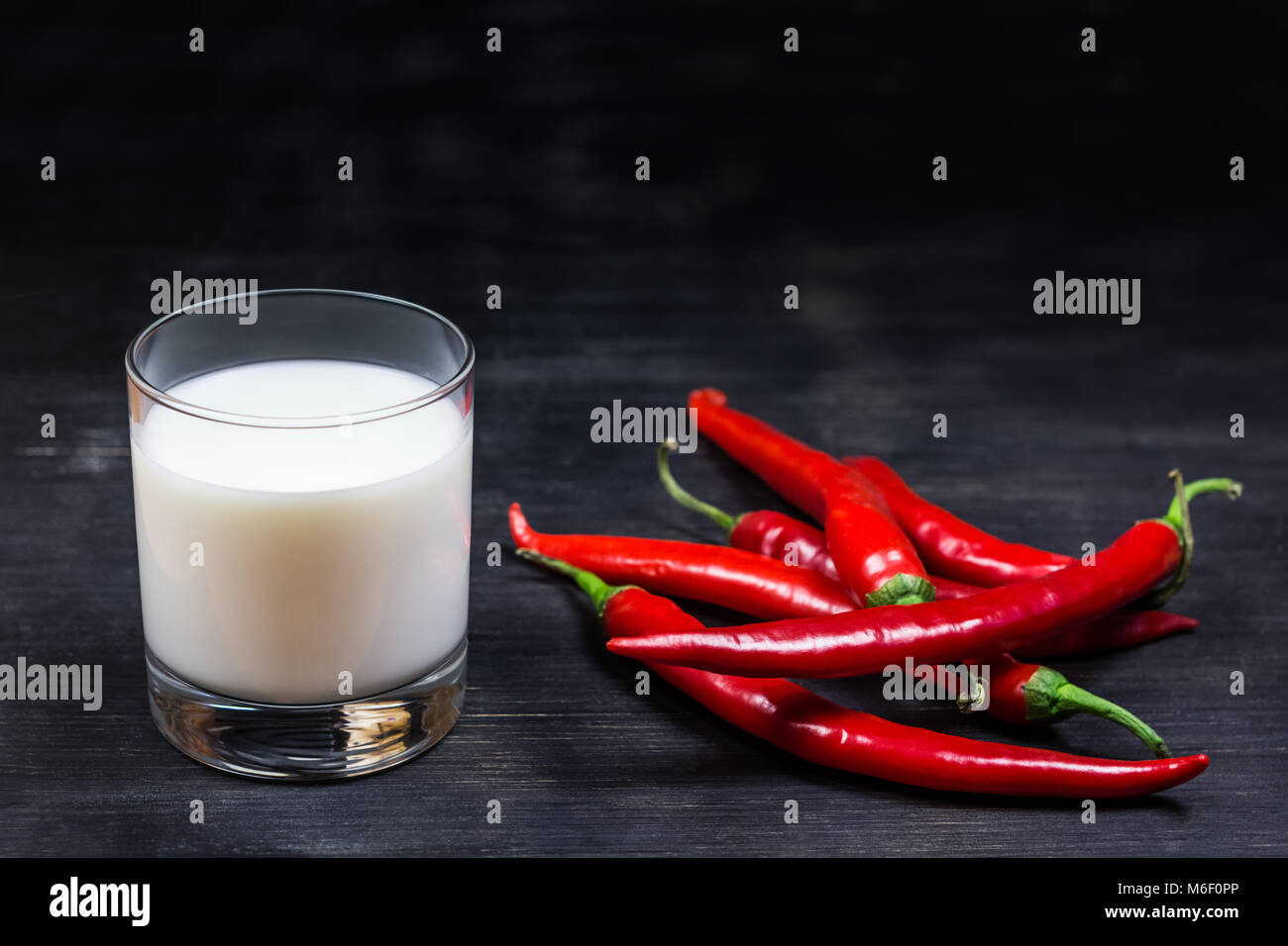 Chili peppers and milk on black background Stock Photo