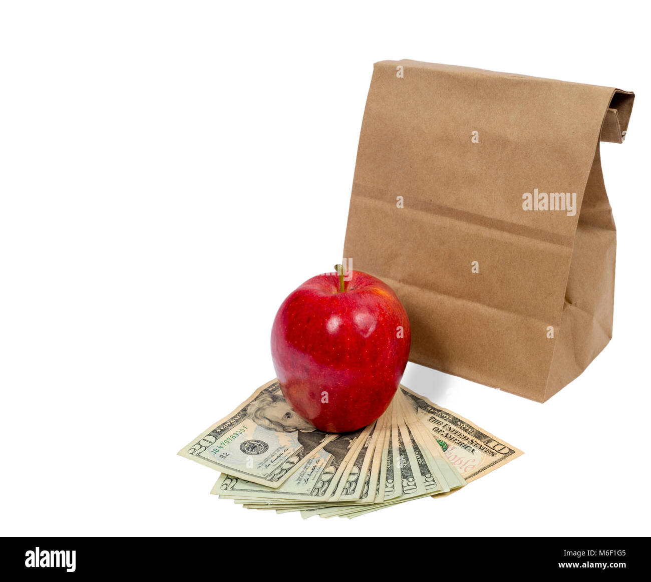 Horizontal shot of the back of a brown paper bag with the top folded down.  In front of this is a red shiny apple sitting on fanned out twenty and ten Stock Photo