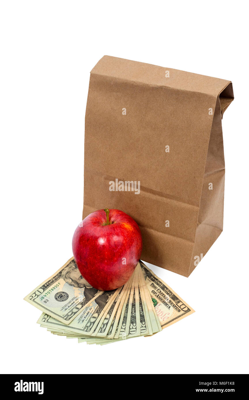 Vertical shot of the back of a brown paper bag with the top folded down.  In front of this is a red shiny apple sitting on fanned out twenty and ten d Stock Photo