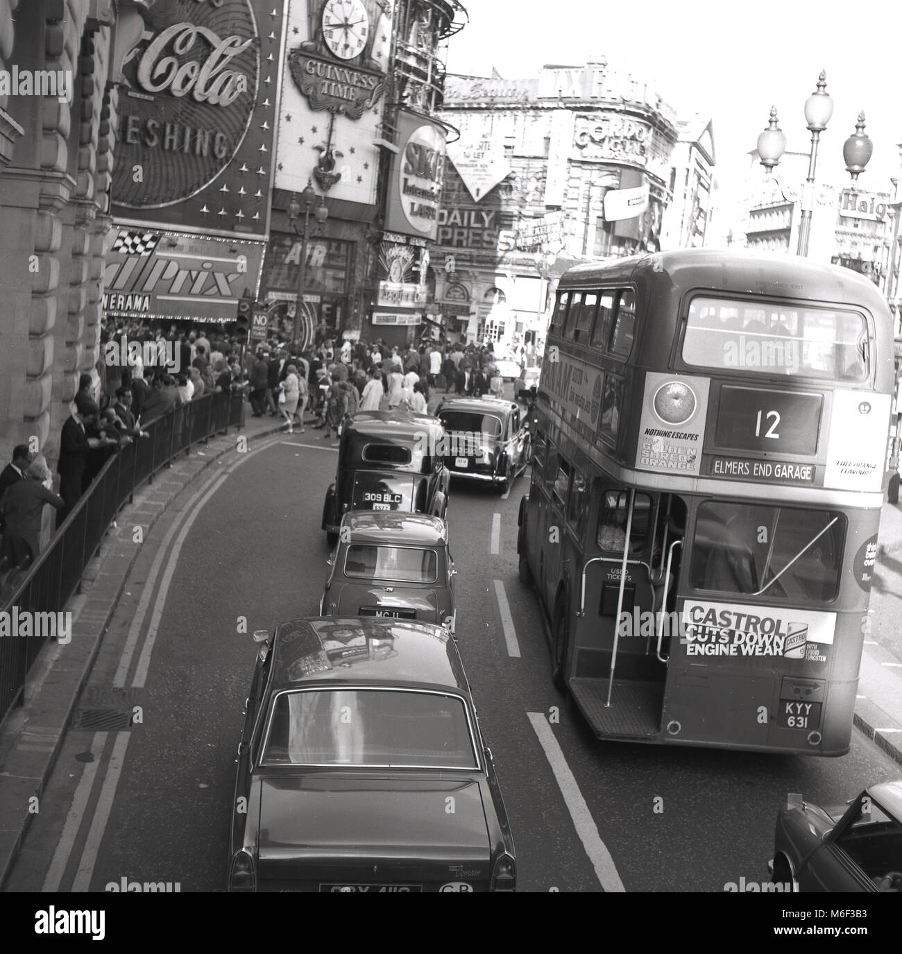 1960s, historical picture showing motor vehicles, including cars, taxis and a routemaster bus, heading towards a busy Piccadilly Circus, crowded with people, London, England, UK. Stock Photo