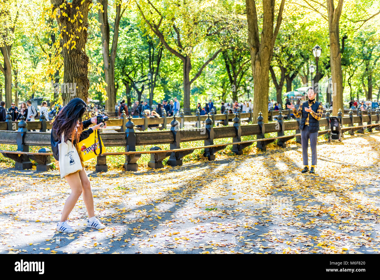 New York City, USA - October 28, 2017: Manhattan NYC Central park with people standing on road in autumn fall season with fallen leaves on ground, asi Stock Photo