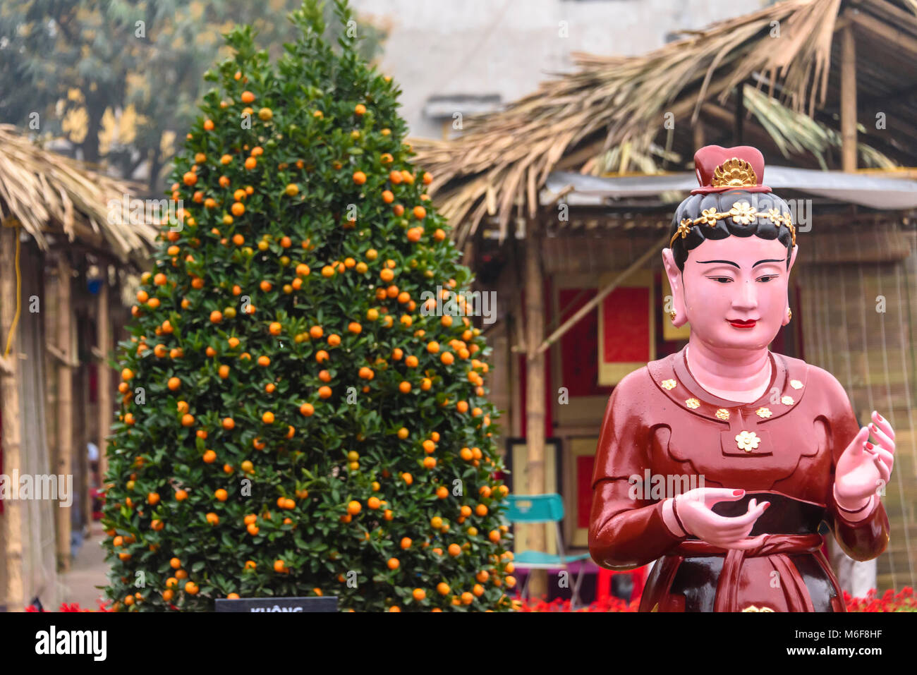 A statue celebrating the Chinese New Year beside a kumquat tree in Hanoi, Vietnam Stock Photo
