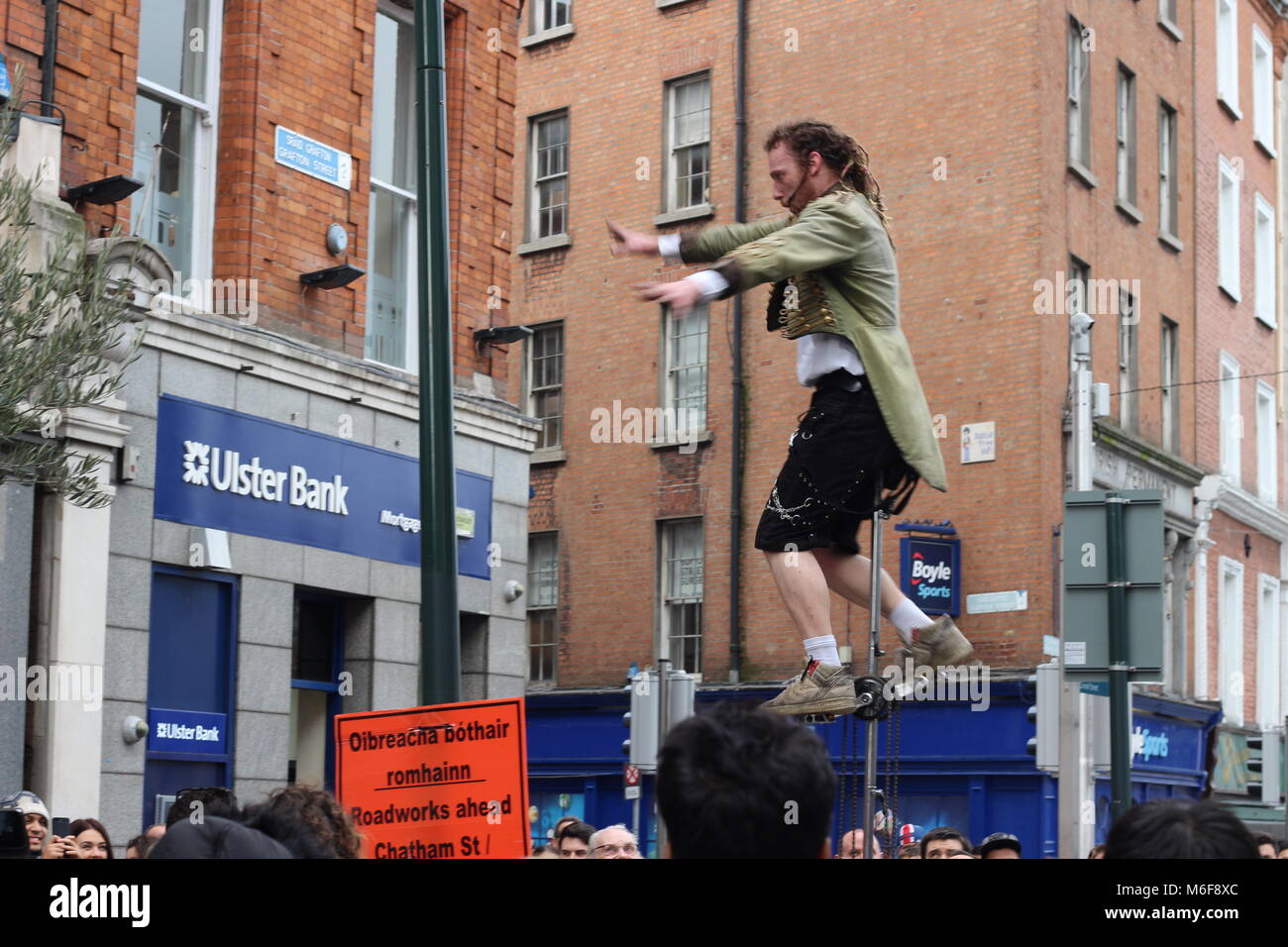 A street performer is on a unicycle doing a performance on Grafton street. The informal economy