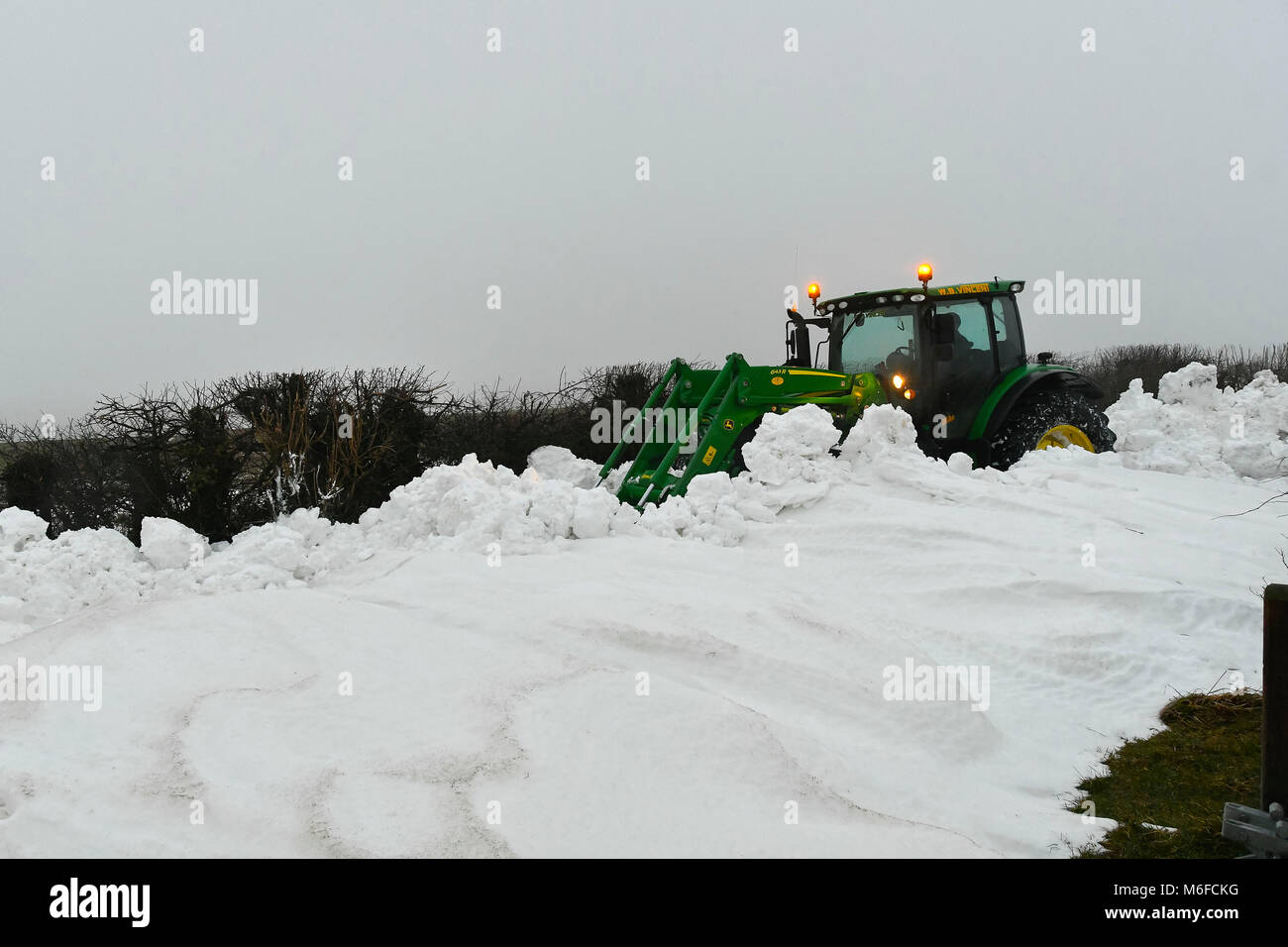 Compton Valence, Dorset, UK.  3rd March 2018.  UK Weather.  A contractor with a tractor and digger attachment clearing the last of the roads blocked by snow drifts from Strom Emma on Eggardon Hill near West Compton in Dorset.  The snow is begining to thaw with most of the fields almost snow free but the drifts along the roads remain and in places are 4-5 feet high.  Picture Credit: Graham Hunt Photography Credit: Graham Hunt/Alamy Live News Stock Photo