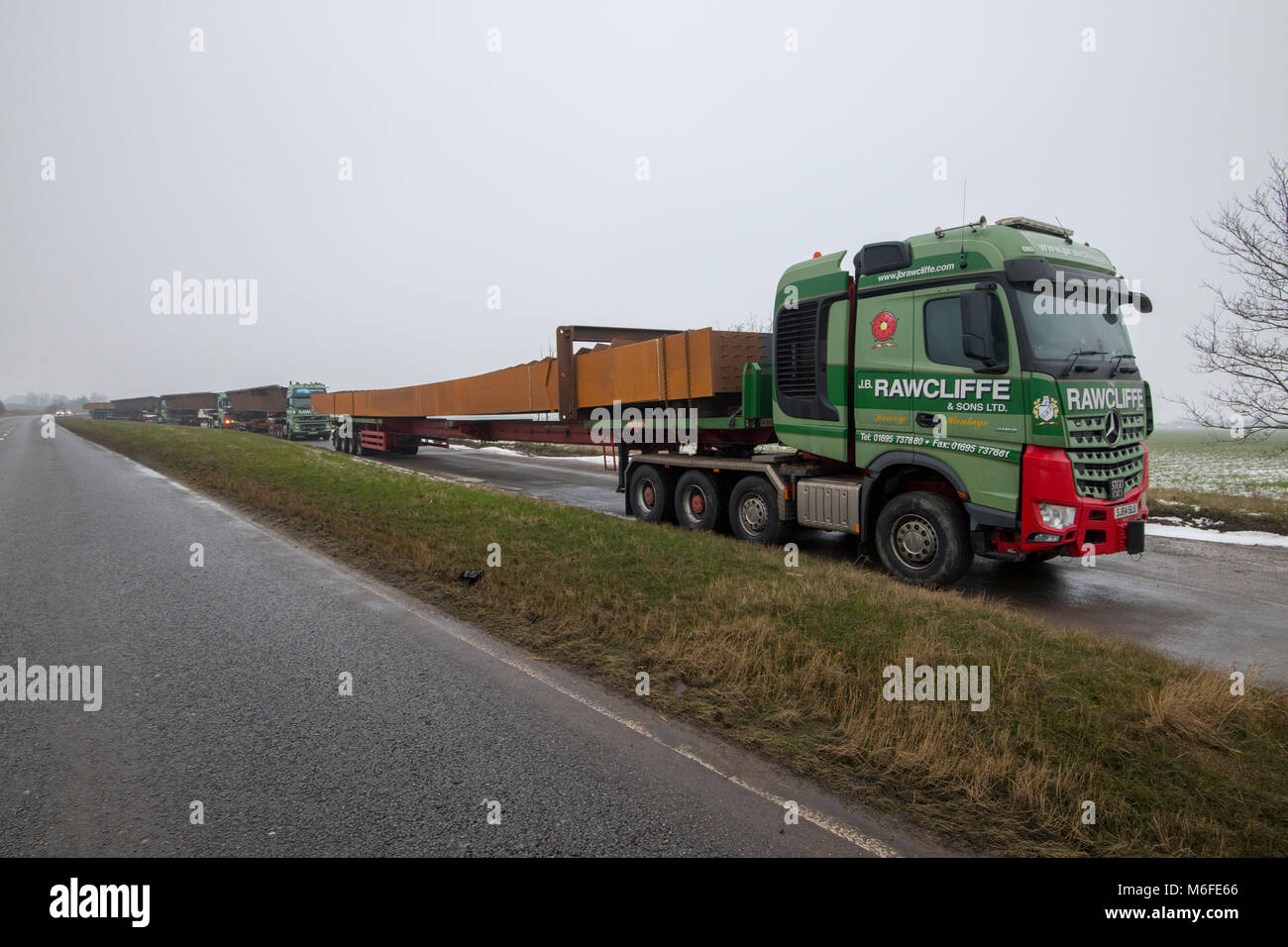 Heavy haulage trucks carrying metal for bridge construction for the