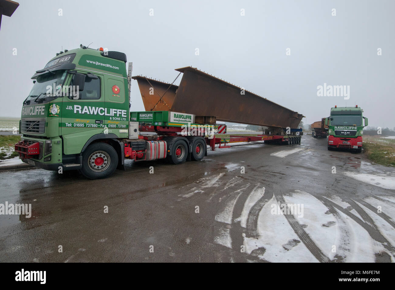 Heavy haulage trucks carrying metal for bridge construction for the