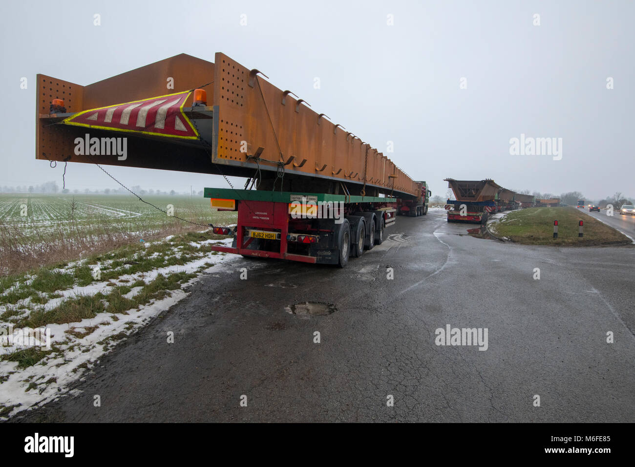 Heavy haulage trucks carrying metal for bridge construction for the