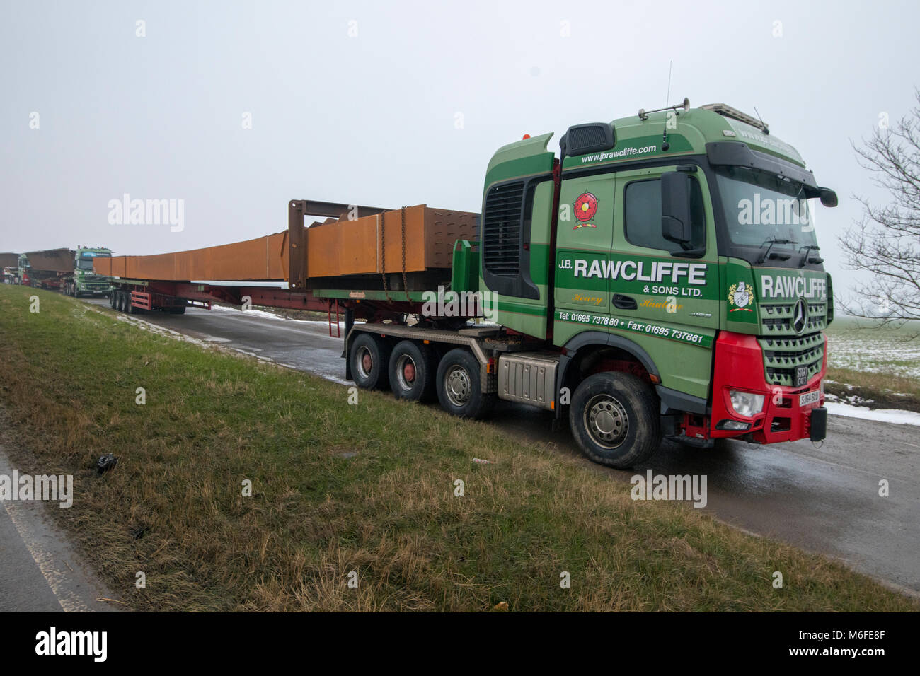 Heavy haulage trucks carrying metal for bridge construction for the