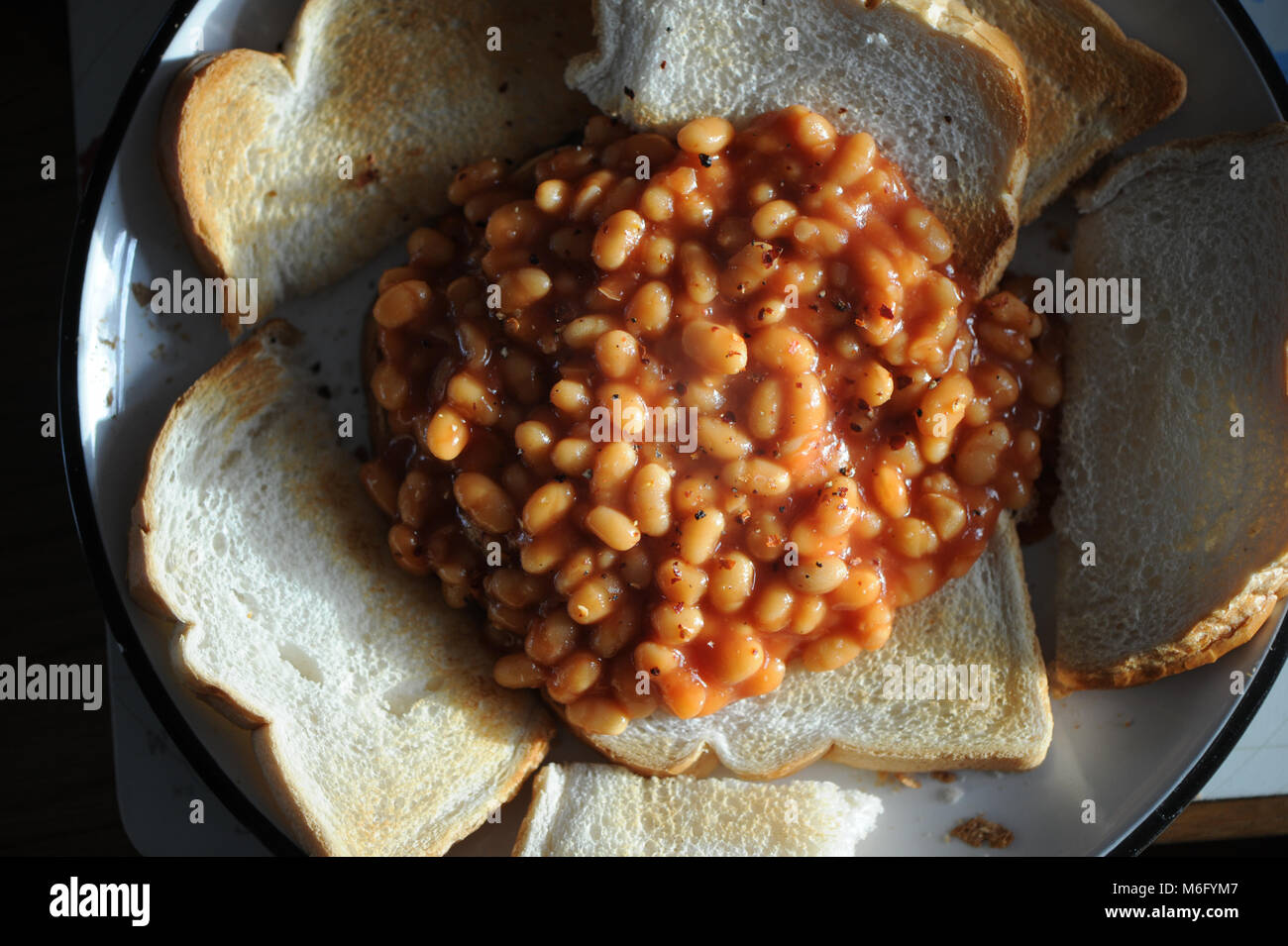 A pile of beans on toast  with chilli flakes sprinkled on top as a lunch snack. Stock Photo