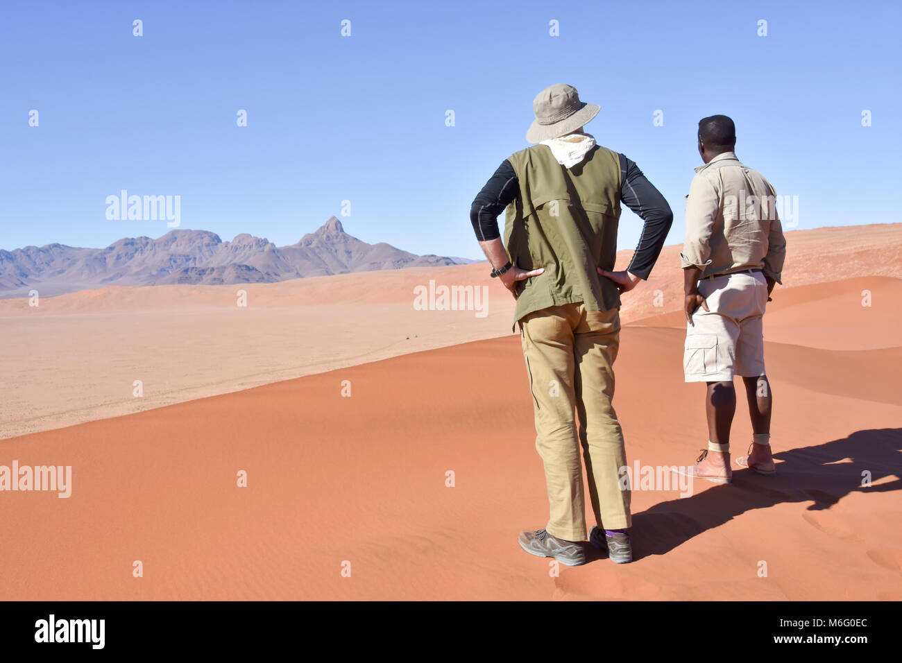 Tourists and a park ranger overlooking the valley from a sand dune in ...