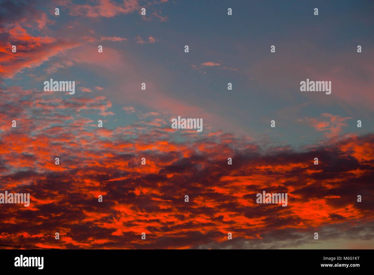 Dramatic sunset sky with clouds painted in vivid red and orange tones ...