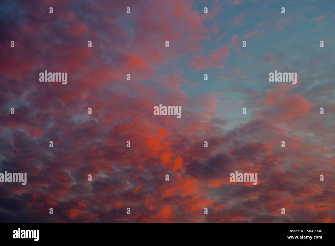 Dramatic sunset sky with clouds painted in vivid red and orange tones ...