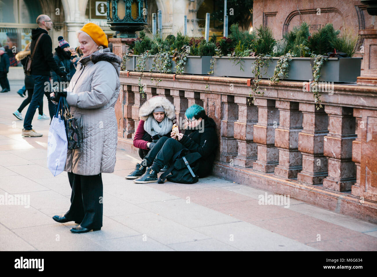 Munich, Germany, December 29, 2016: Two punk girls sit and eat in the central square in Munich. Subculture. Everyday routine life in Europe. Homeless, rebels. Stock Photo