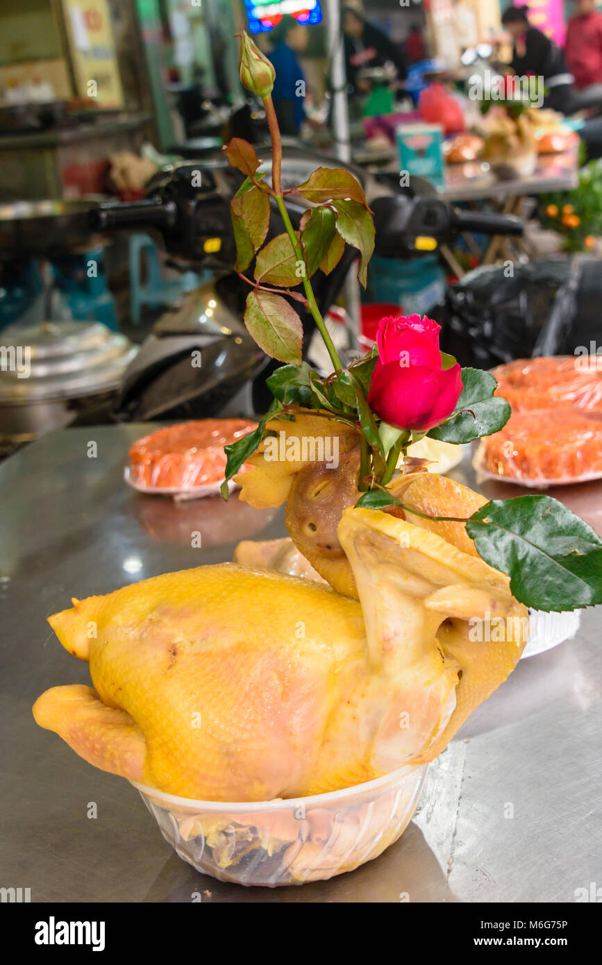 A chicken carcase with a red rose stuck down its throat on a table outside a restaurant in Hanoi, Vietnam Stock Photo