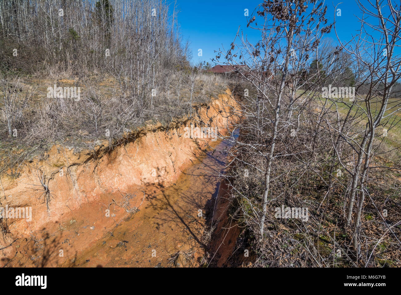 A natural watershed cut through Mississippi red clay dirt. Stock Photo