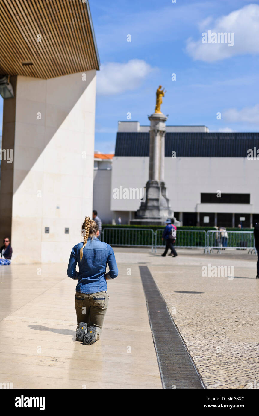 A young female devotee walking slowly on her knees at the Sanctuary of Fatima, Portugal Stock Photo
