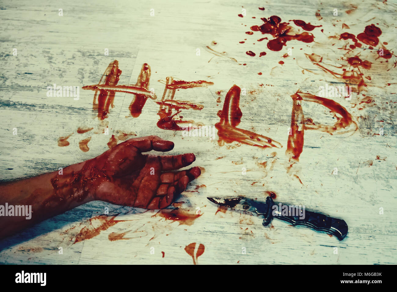 Says help, written in red blood on the dirty white floor of the bloody hand. The murder victim asks for help. Stock Photo