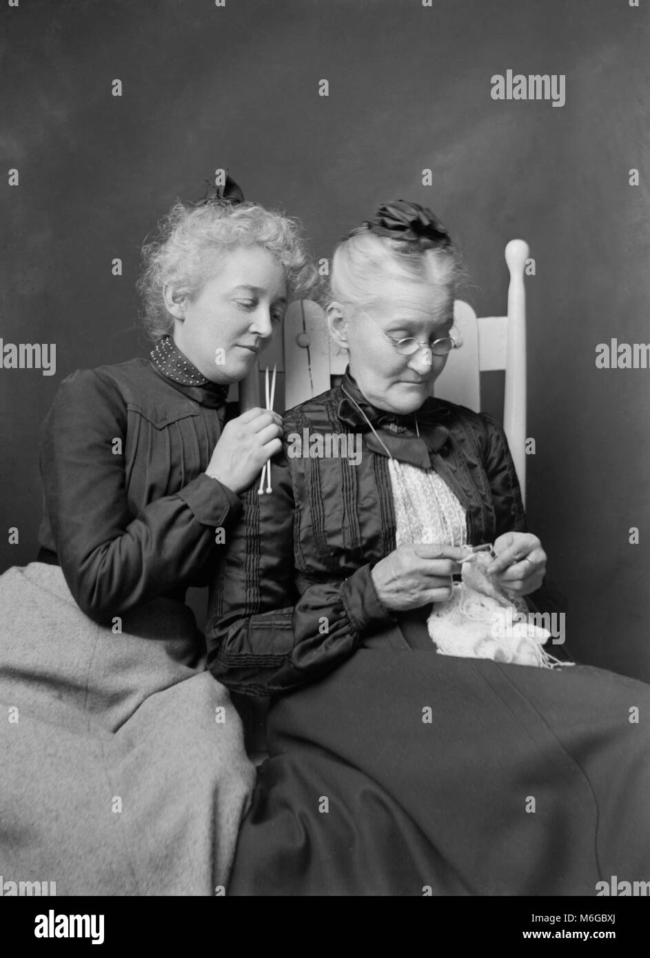 Senior mother and adult daughter knit together, ca. 1900. Stock Photo