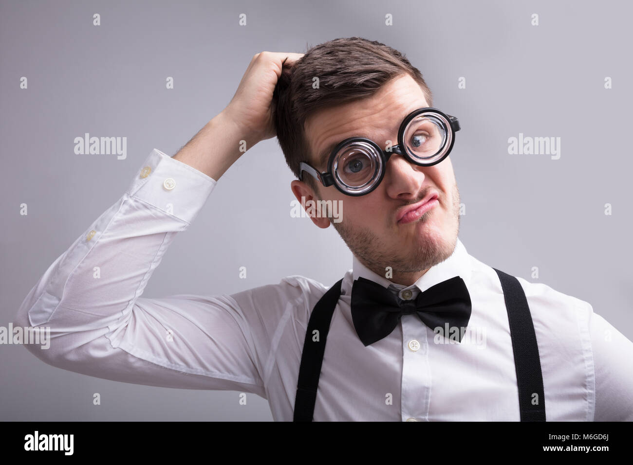 Close-up Of A Contemplated Young Man Against Grey Background Stock Photo