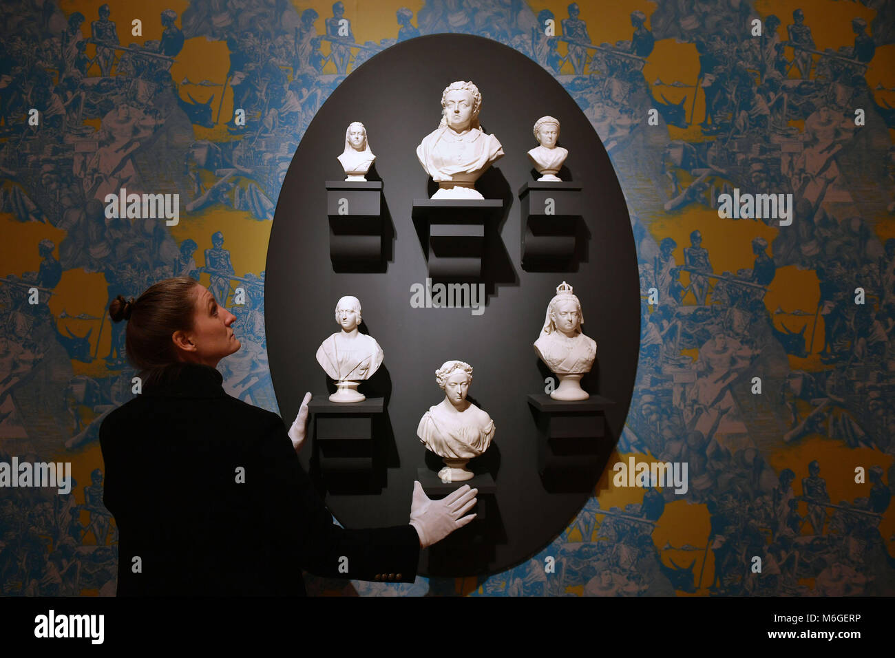 Fitzwilliam Museum's Emma Shaw adjusts parian busts of Queen Victoria against a backdrop of the Bengal Famine in the 'Flux: Parian unpacked' contemporary exhibition by artist Matt Smith, which opens at The Fitzwilliam Museum in Cambridge on March 6. Stock Photo