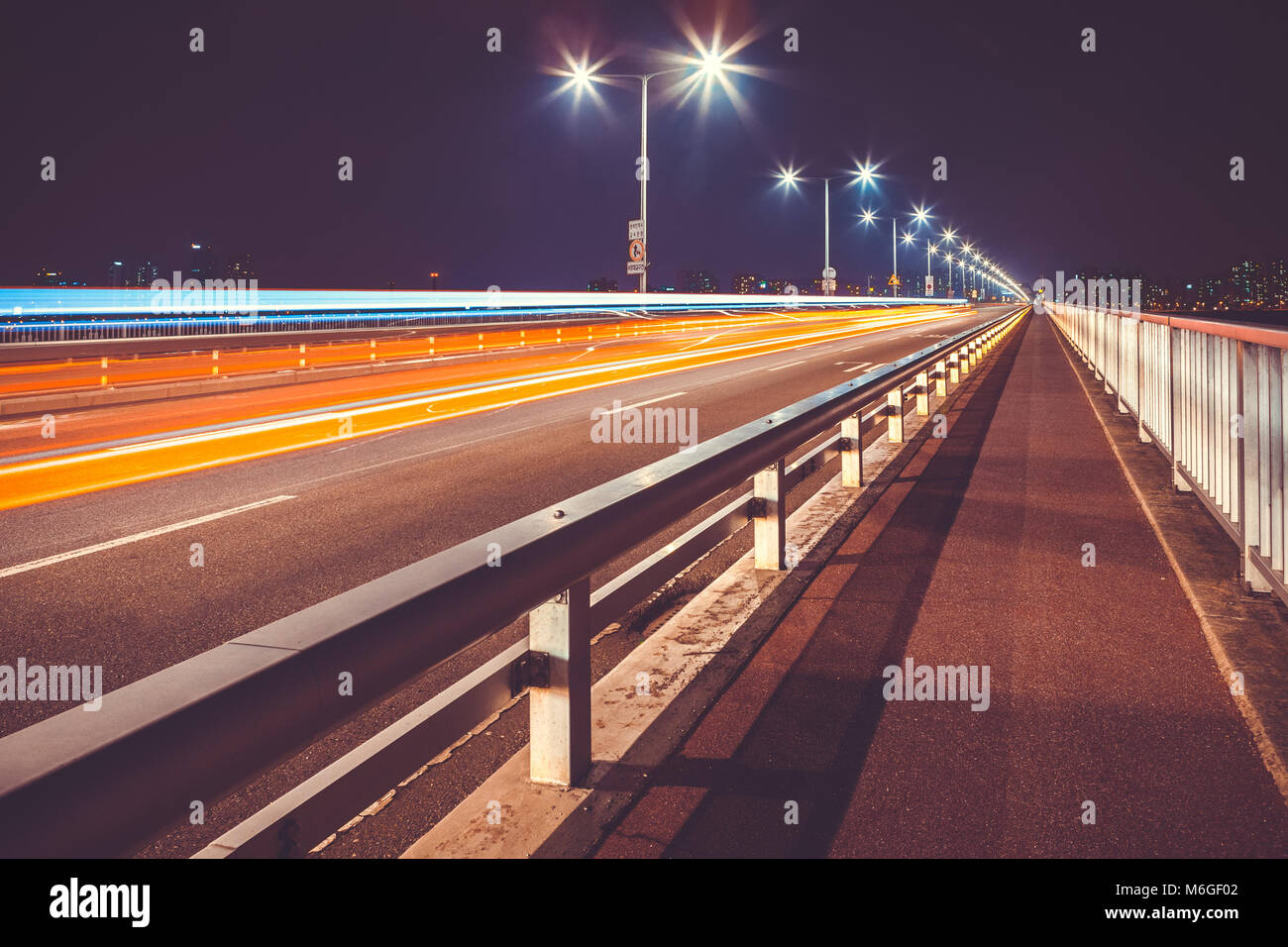 Several cars passing bridge through Han river and leaving lights traces behind them - Seoul, South Korea Stock Photo