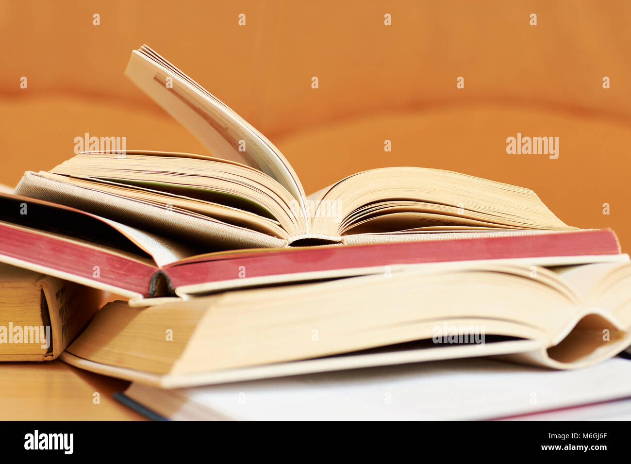 Open books in a hard cover on a table with a blurred orange background Stock Photo