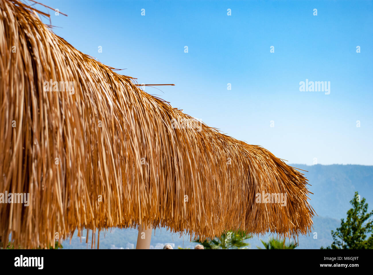 A charming beach bar with a straw thatched roof offers a breezy retreat at a seaside resort Stock Photo